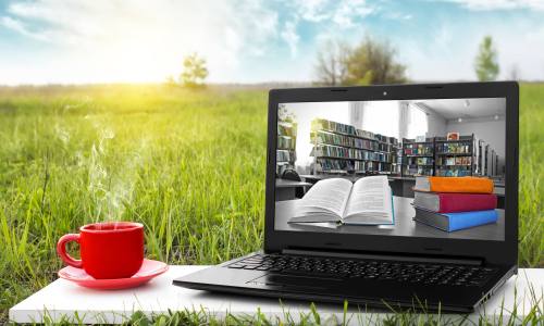 Laptop and cup of hot coffee on the background picturesque nature, outdoor office. E-book library concept with laptop computer and book. Old books on a wooden shelf. Travel concept. Business ideas. Online Bibliothek Vulkanland